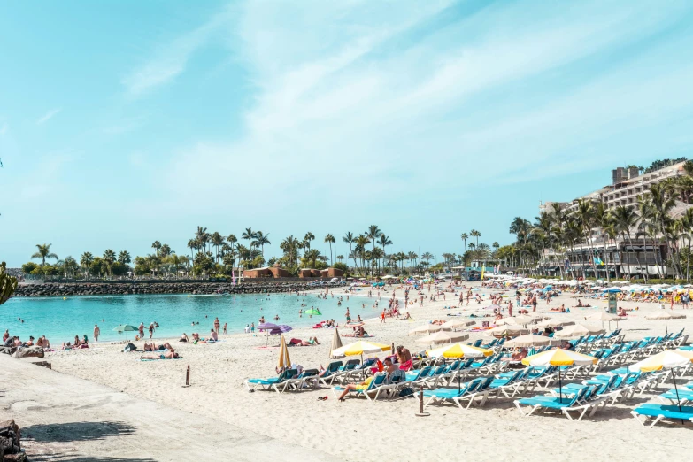 many people are on a beach with several umbrellas