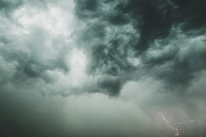 the storm clouds are gathering above and a train is sitting on tracks