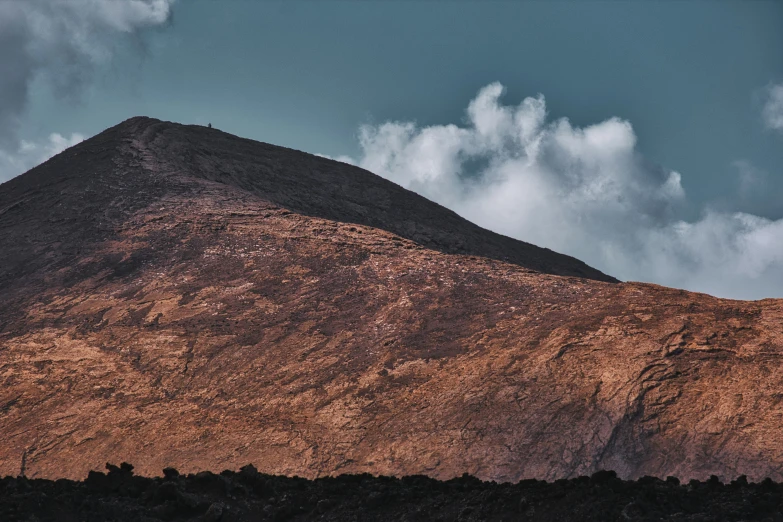 mountain side view of brown mountain under cloudy skies