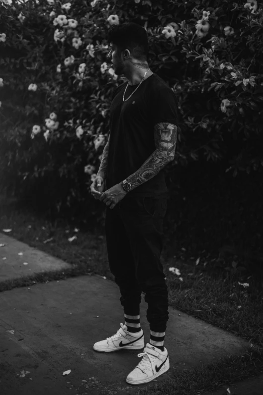 a man standing on a sidewalk in front of some flowers