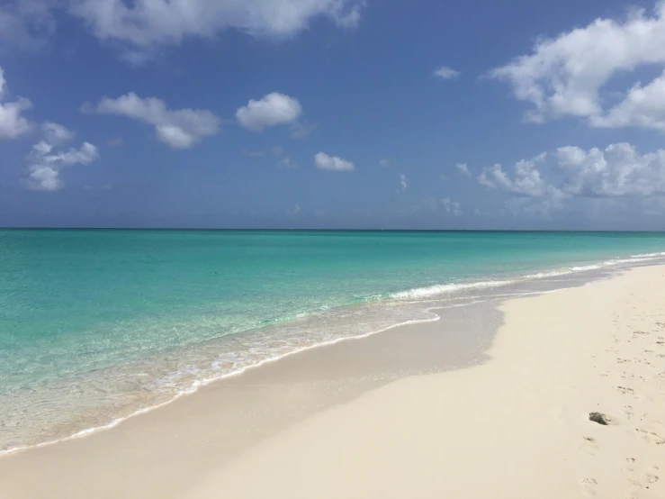 a beach with blue water and white sand on a cloudy day