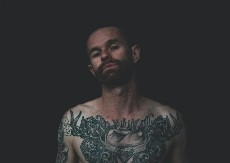 a man with his arm tattoo in front of a black background