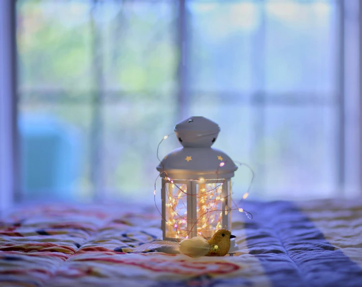 a lantern with small lights sitting on top of a bed