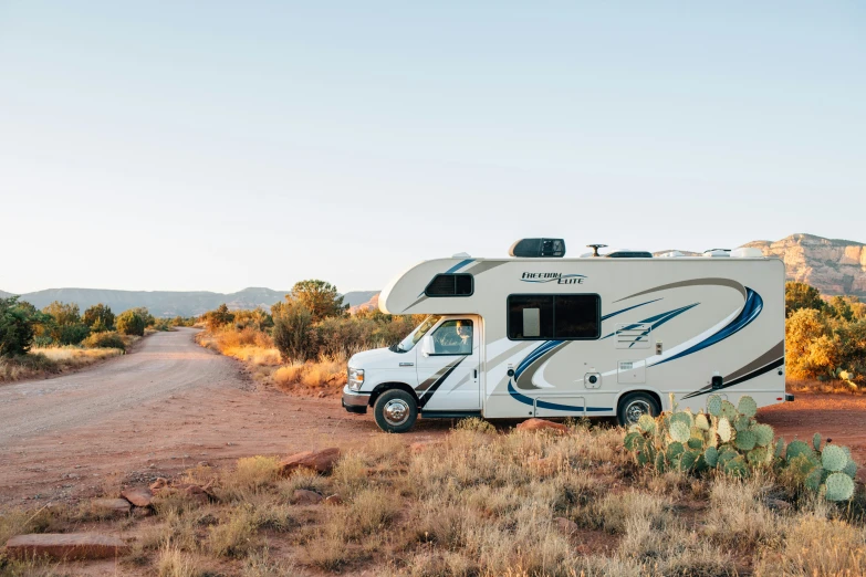 a large white camper in the middle of a dirt road