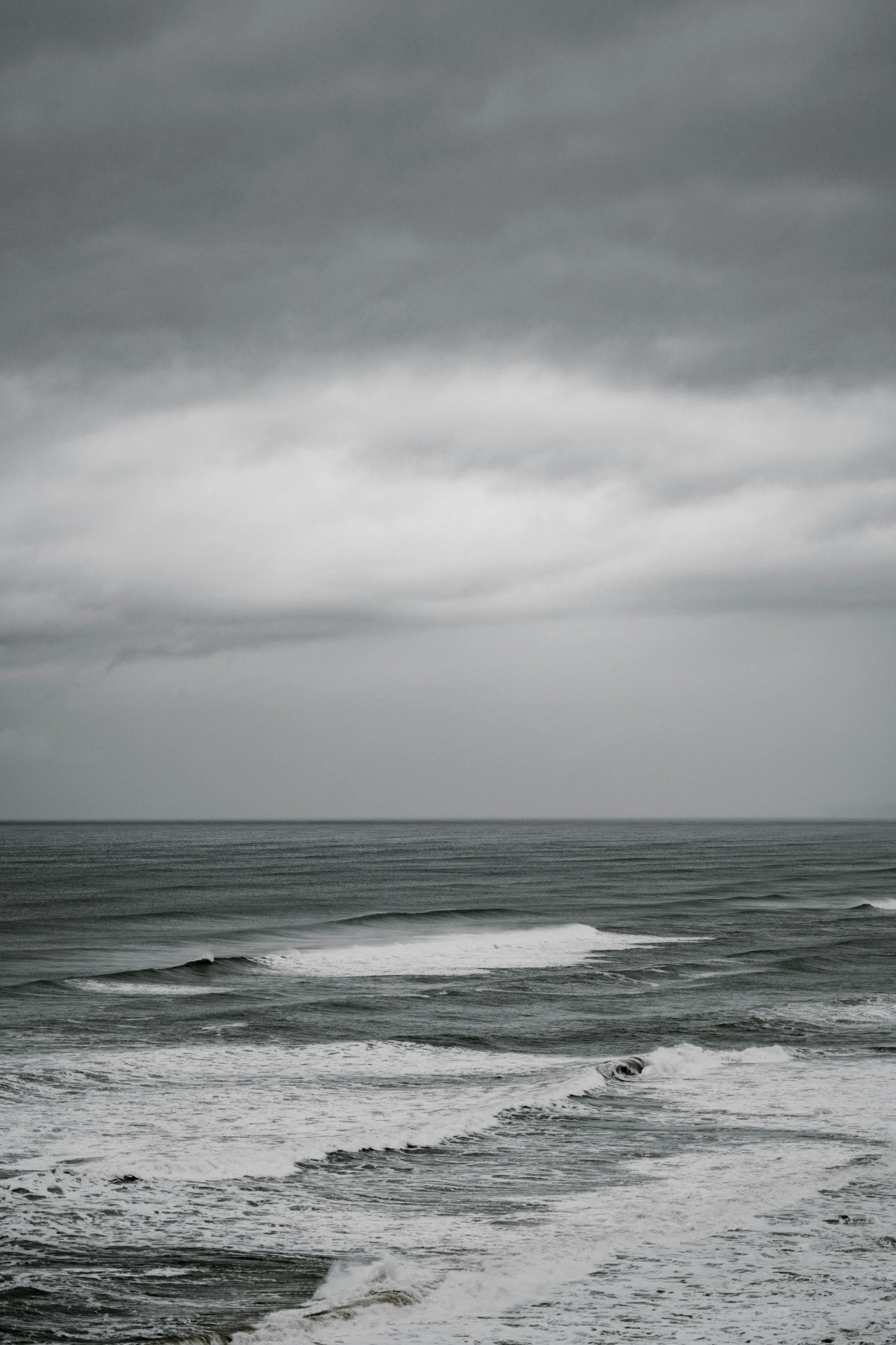 the man is walking his surf board into the water