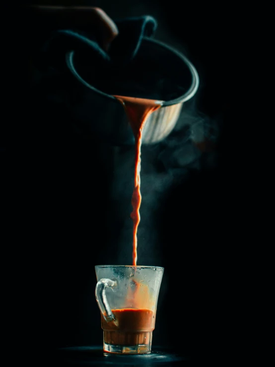 liquid poured onto a cup in a black room