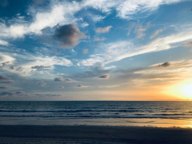 the sky is setting at a beach in front of the ocean