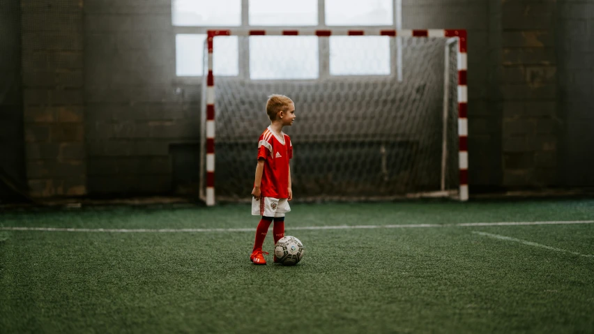 a young man standing in front of a soccer ball