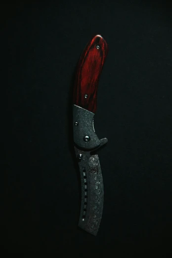 a knife with red and silver handles in a dark room