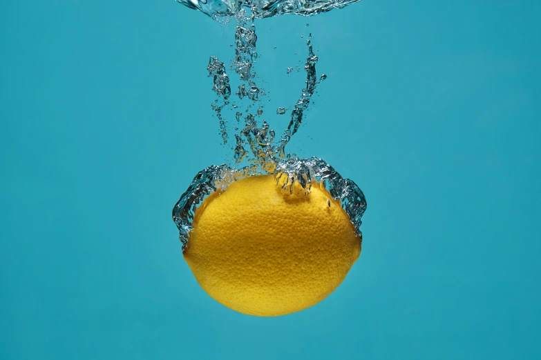 a lemon submerged in water with a splash