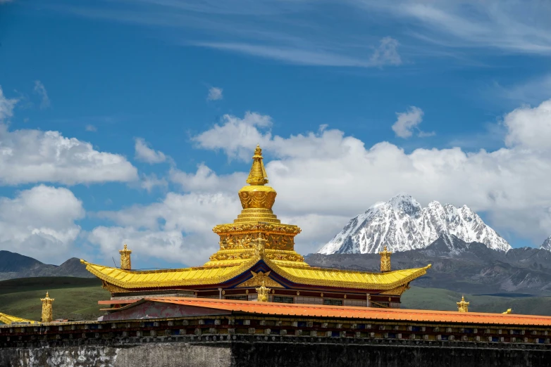 a golden building with mountains in the background