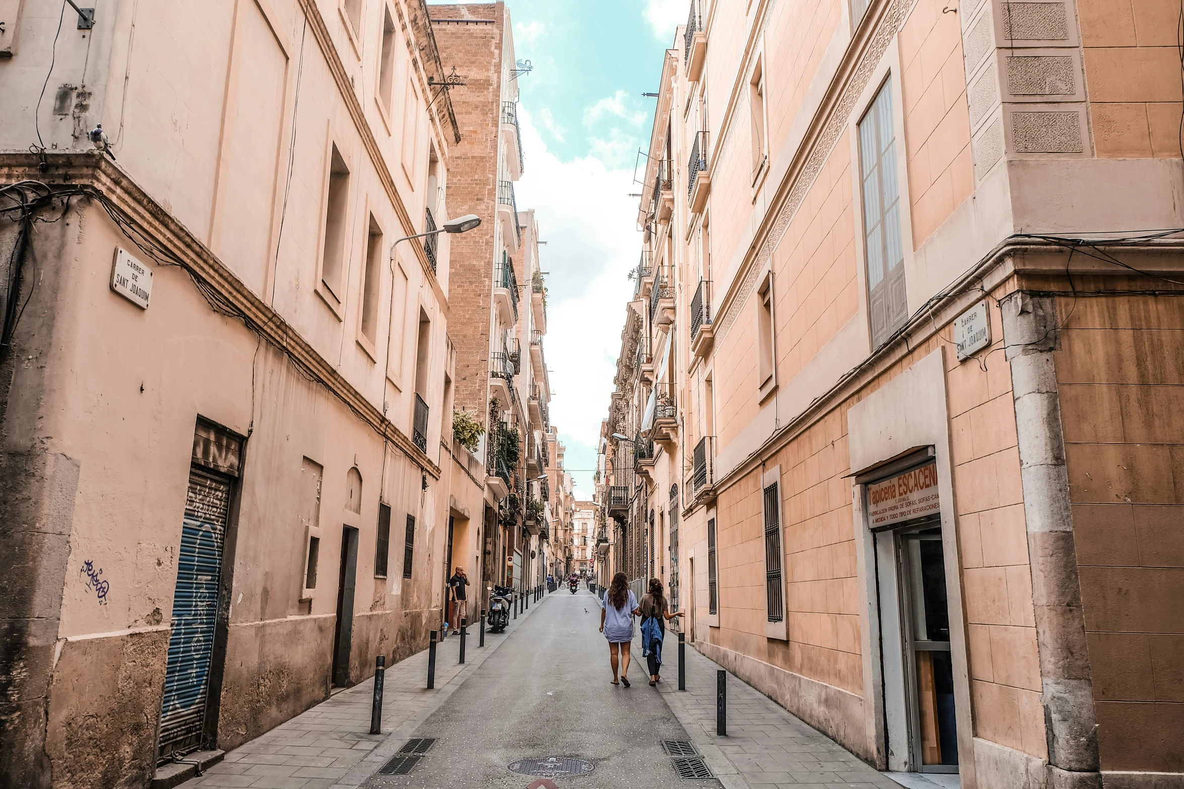 a narrow city street has people walking down it