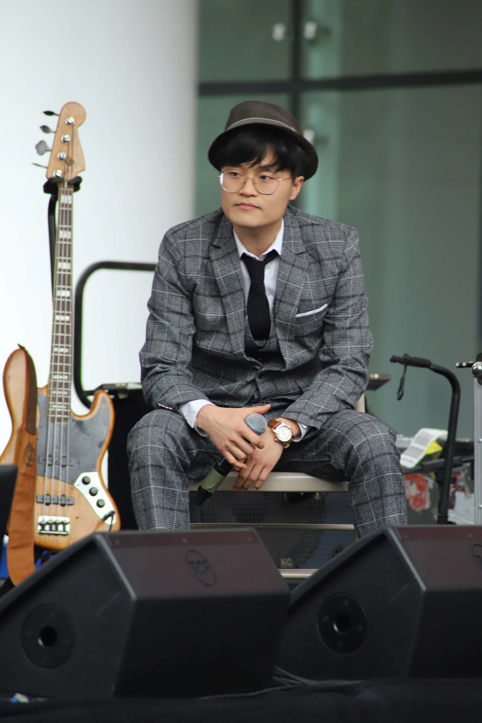 a man in a suit and hat sits on a bench