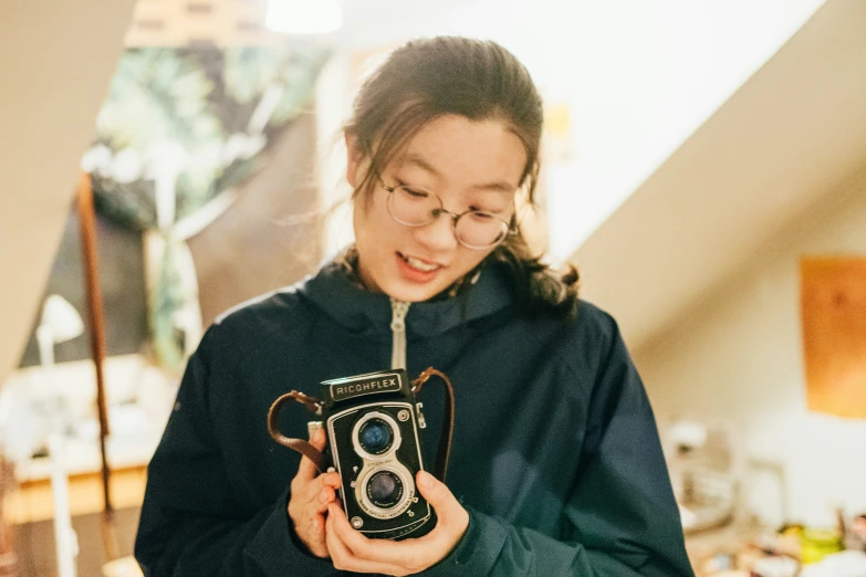 young woman holding up an old fashioned camera