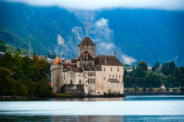 a large castle with a flag on the top sits next to water