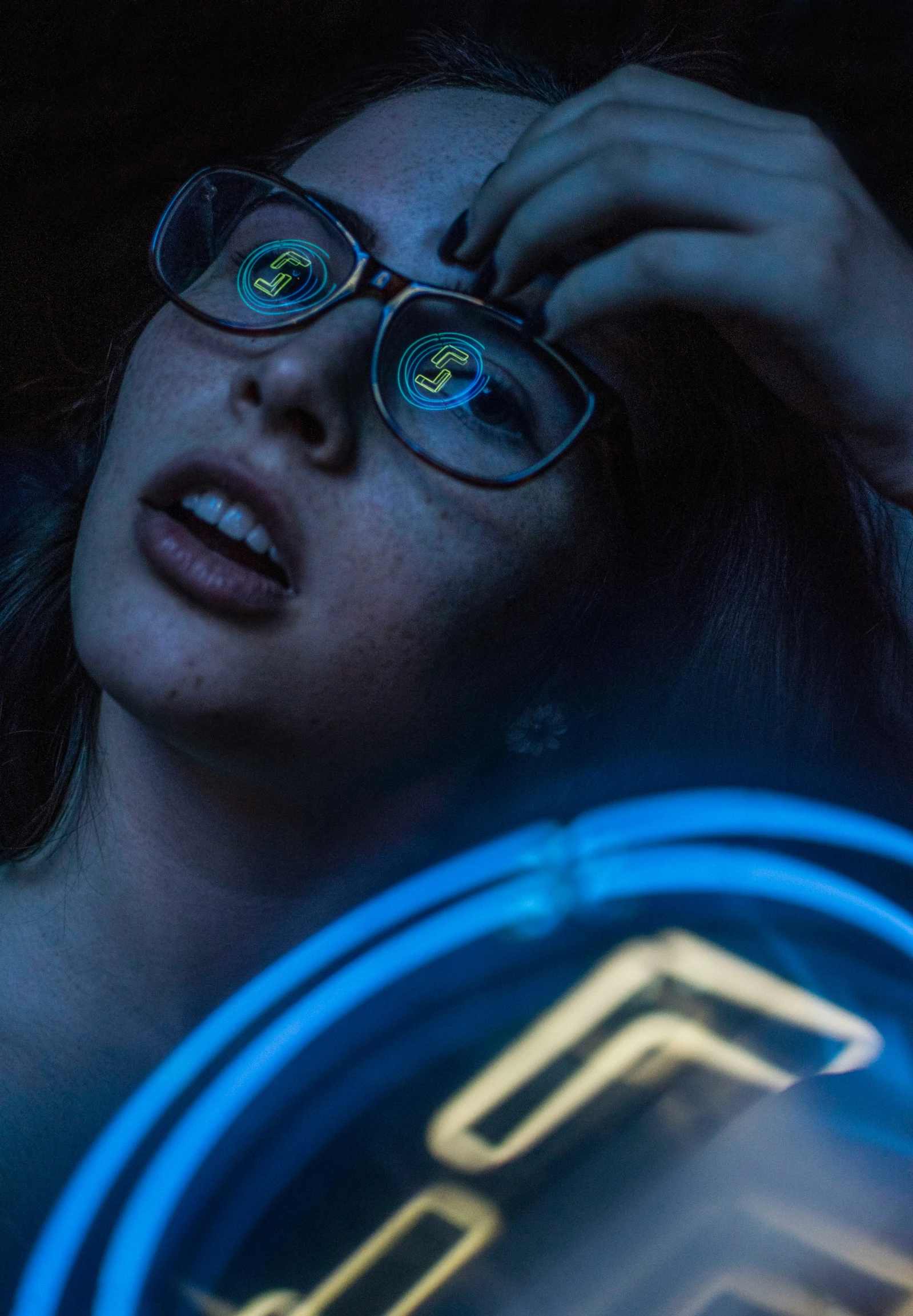 a woman wearing glasses holding onto her eye with glowing circles