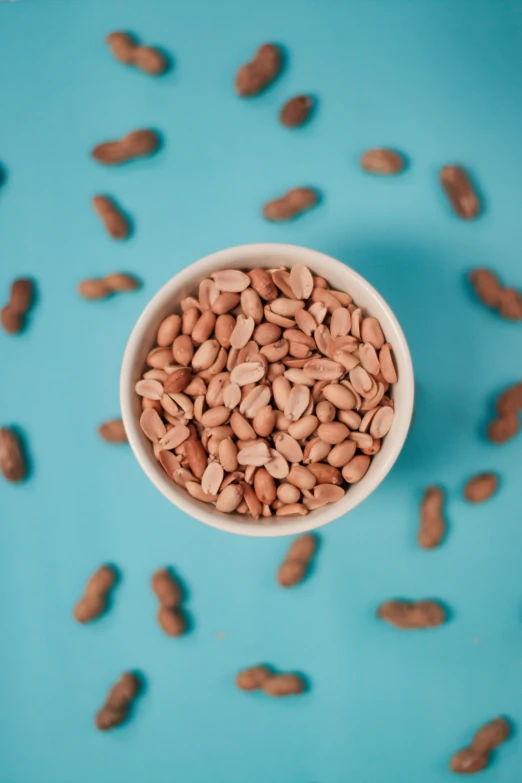 a white bowl filled with nuts on top of blue table