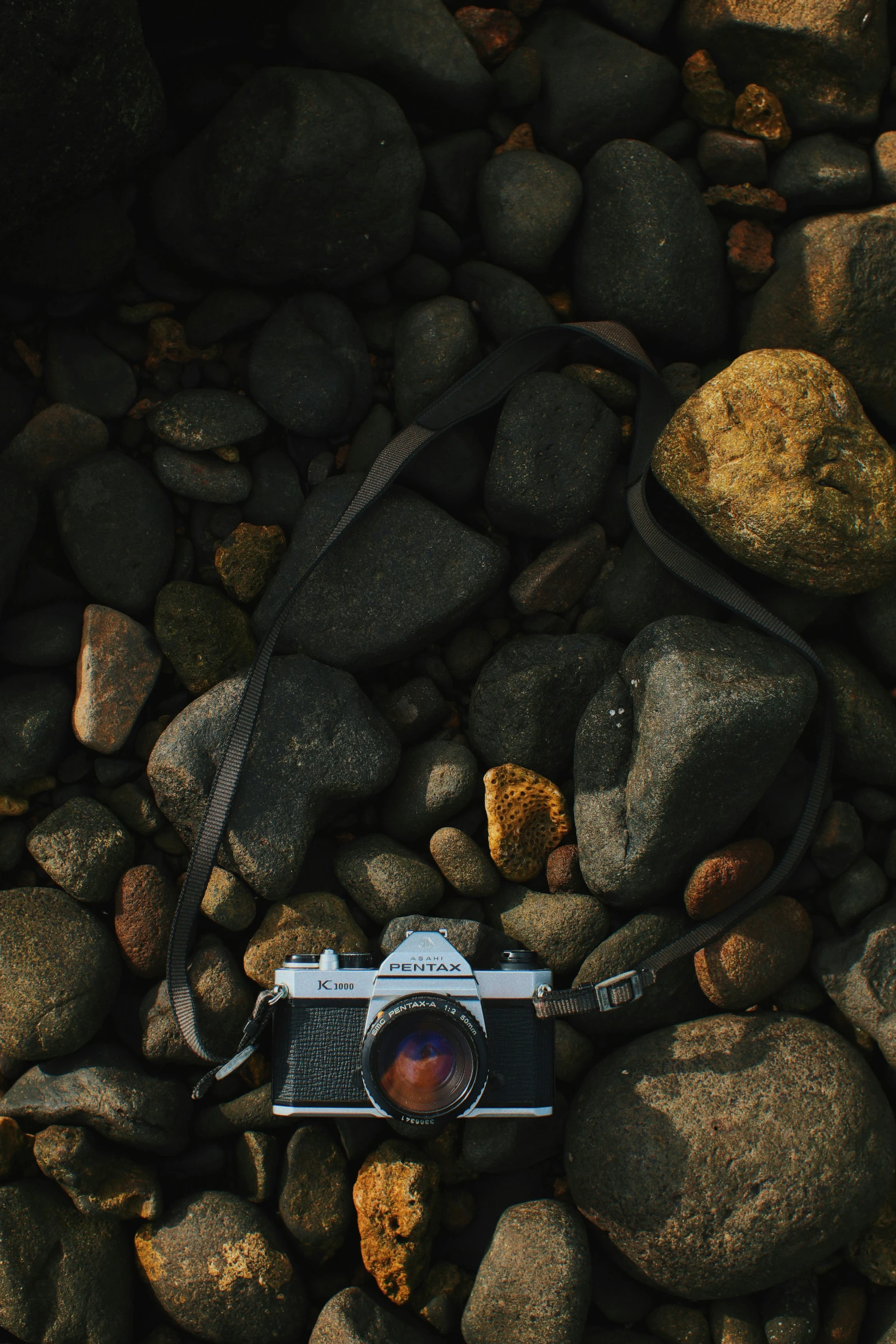 an old camera is laying on rocks near some rocks