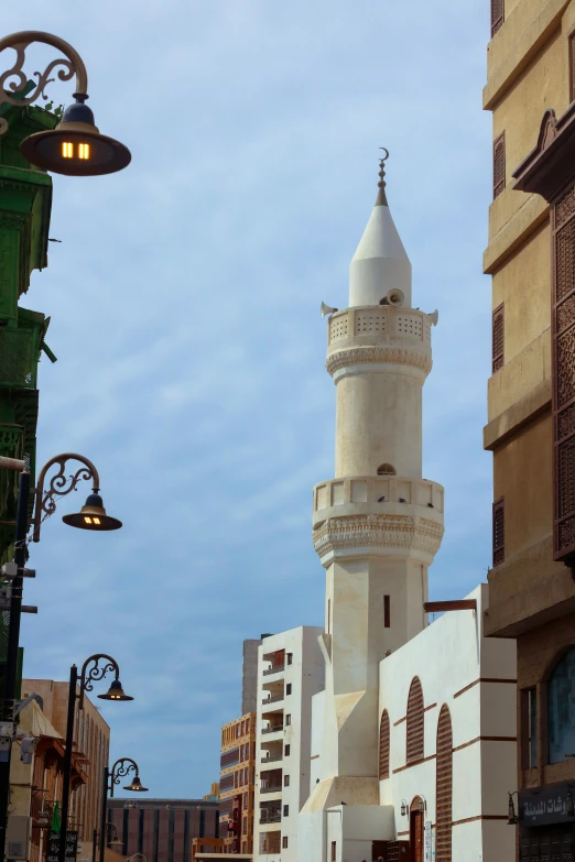 a white clock tower stands next to a green lamp