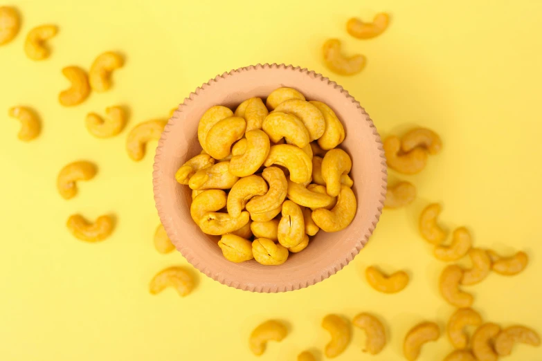 a small pink bowl with yellow powdered cashews