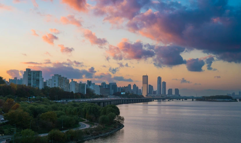 a city skyline is shown as the sun rises over a lake