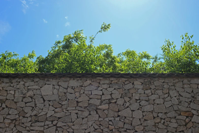 the top of a stone wall with green trees in background