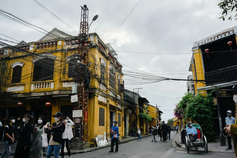 people walk along a street with buildings in the background