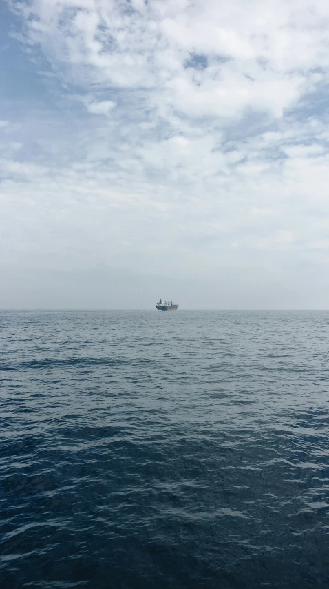 a boat traveling across the ocean under a cloudy sky