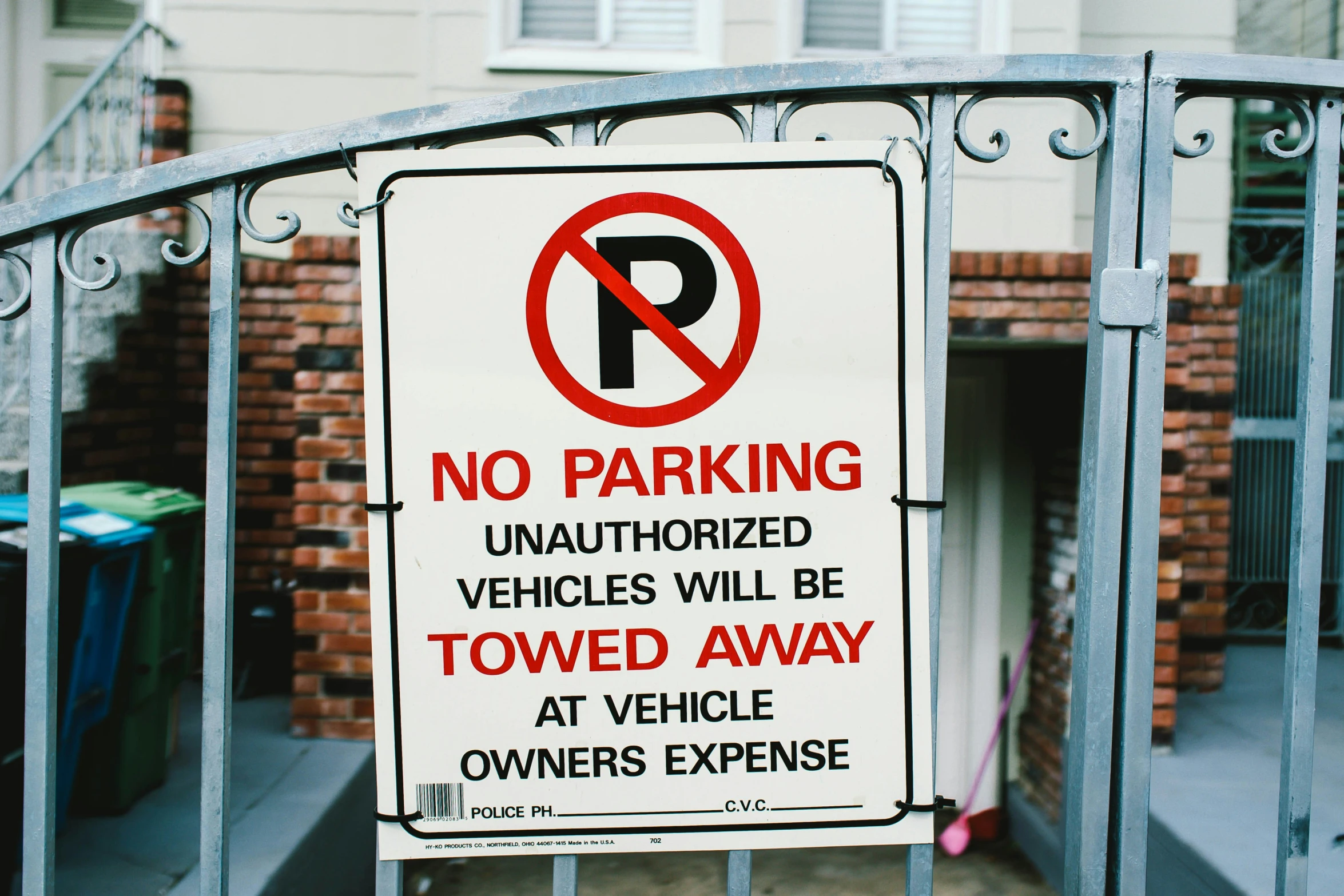 a parking sign attached to an iron fence