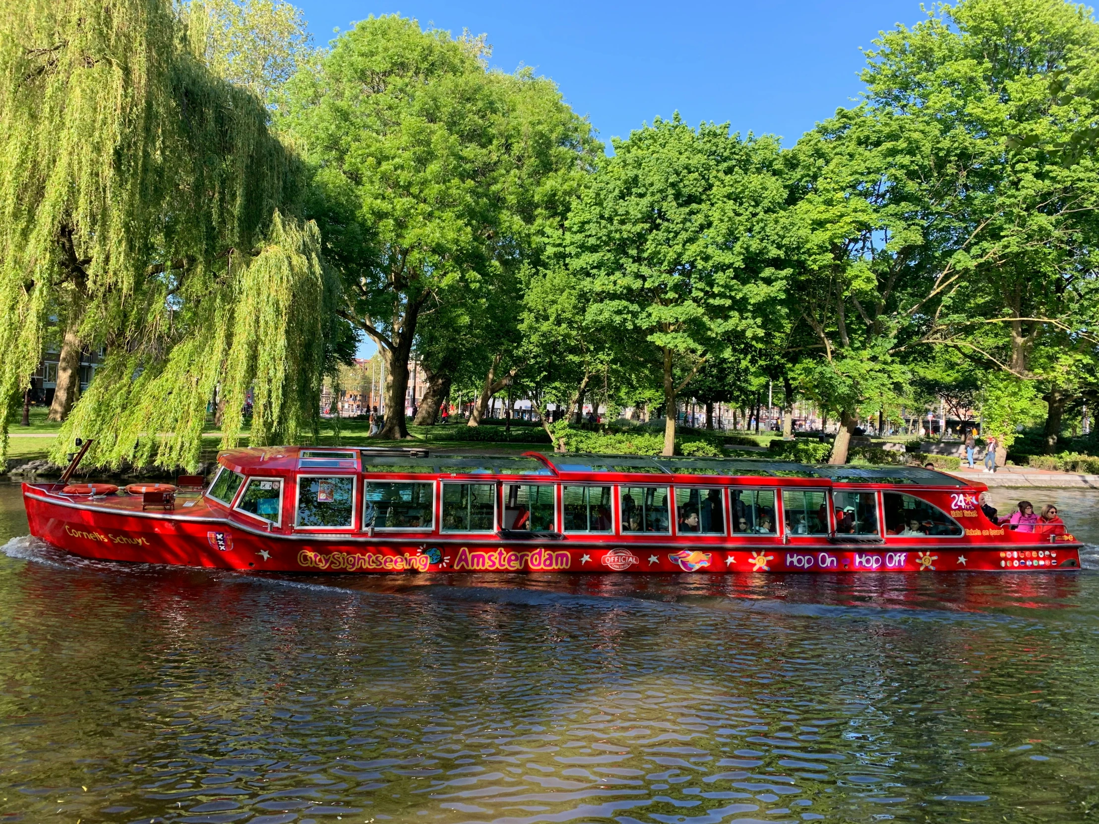 a red tour bus is traveling down the water