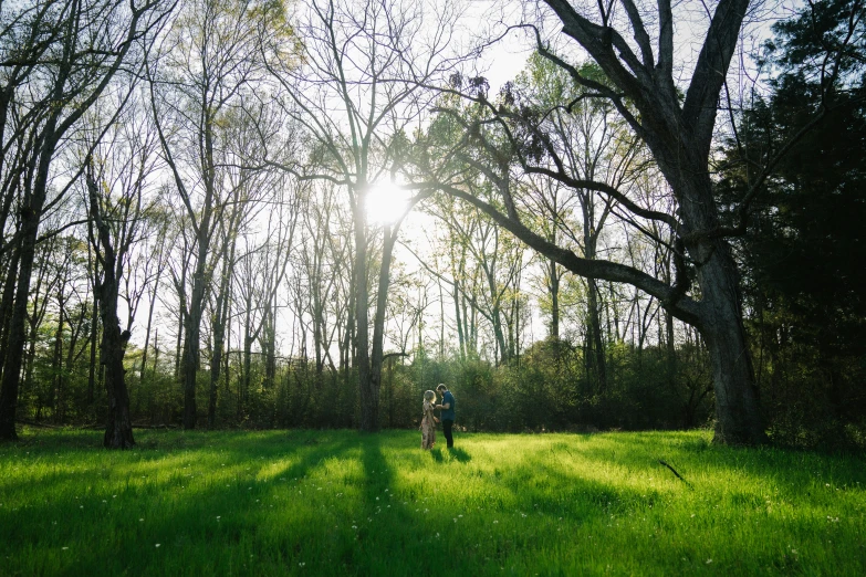 two people in a field with trees and green grass