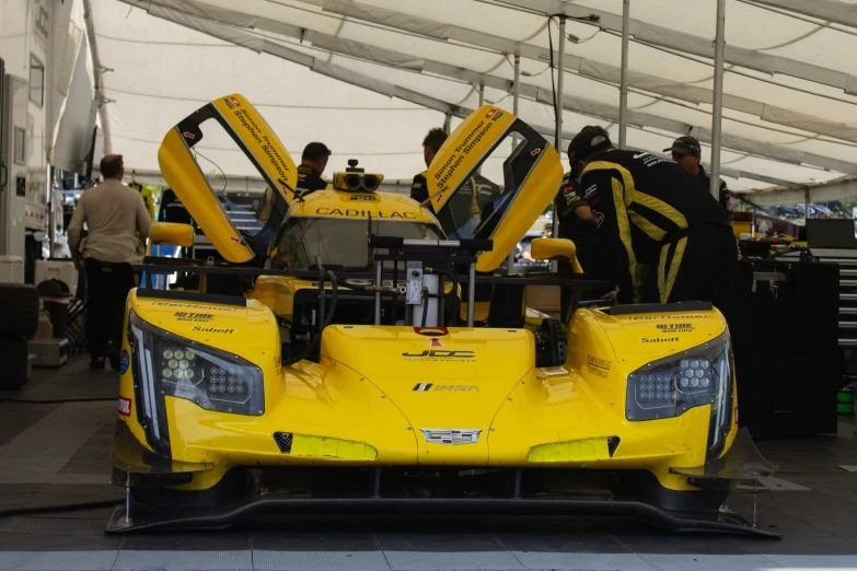 a man inspecting a yellow race car in an event