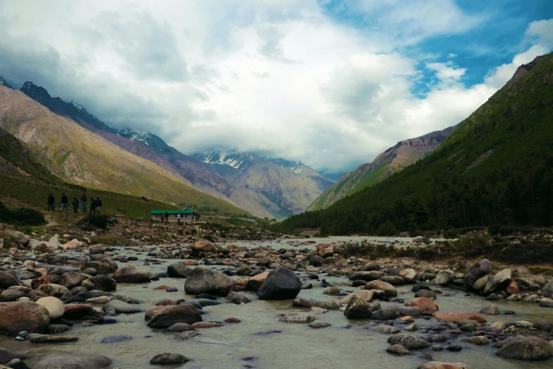 people hiking through a river with mountain in the background