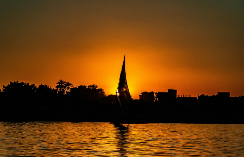 a sailboat traveling in the sunset in the water