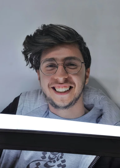 smiling guy wearing glasses and grey sweatshirt holding picture frame
