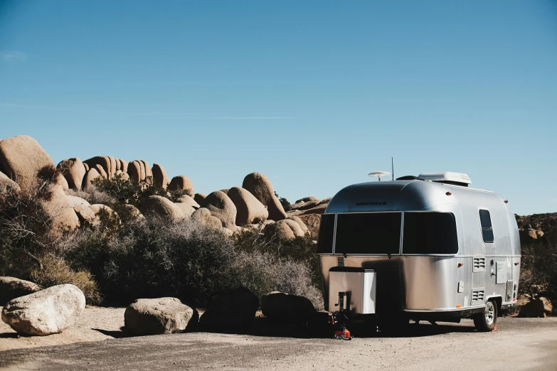 a silver airstream parked in the middle of some grass