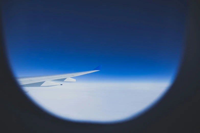 the wing of an airplane flying through the sky