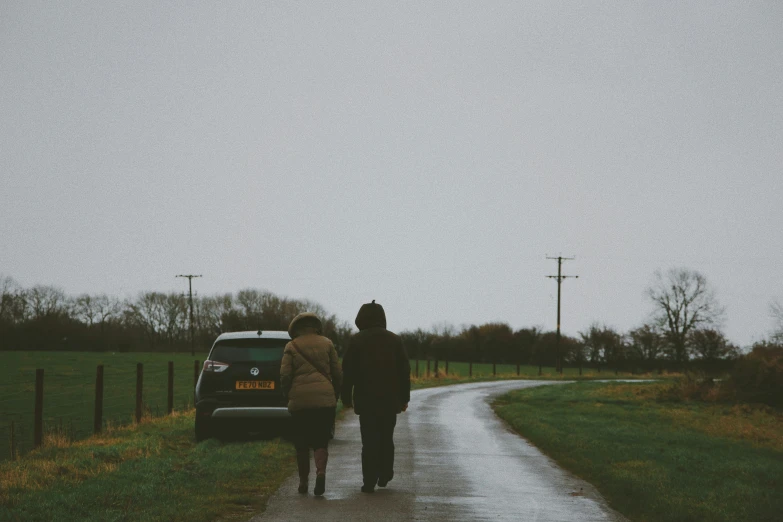 two people walking down a road on a dirt path