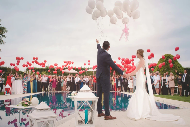 the couple stand on their wedding day as a large crowd looks on