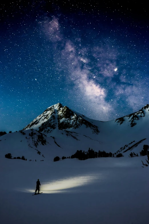 a man standing on top of a snow covered slope under the stars