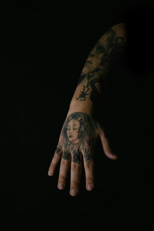 a hand with a face tattoo in the dark