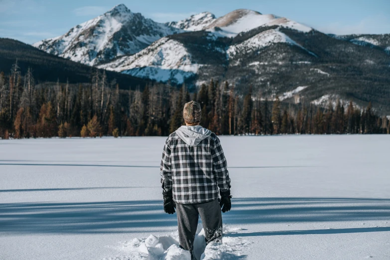 a man in a plaid snowsuit standing on some snow