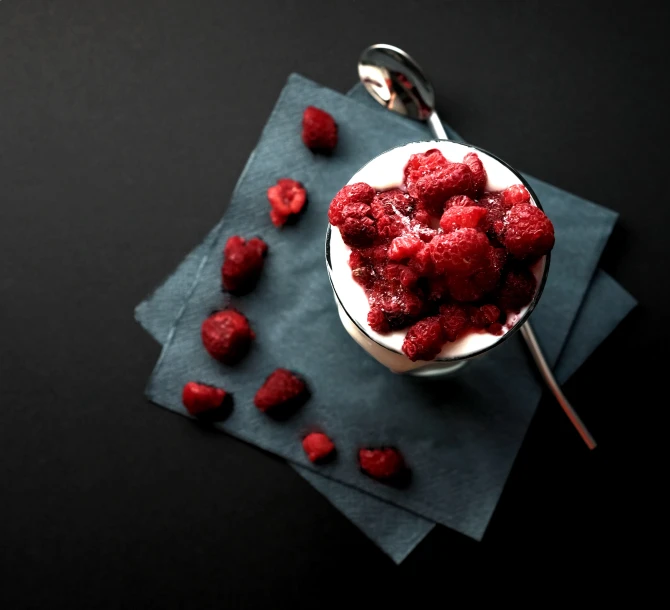 fresh raspberries are placed in a bowl on a black surface