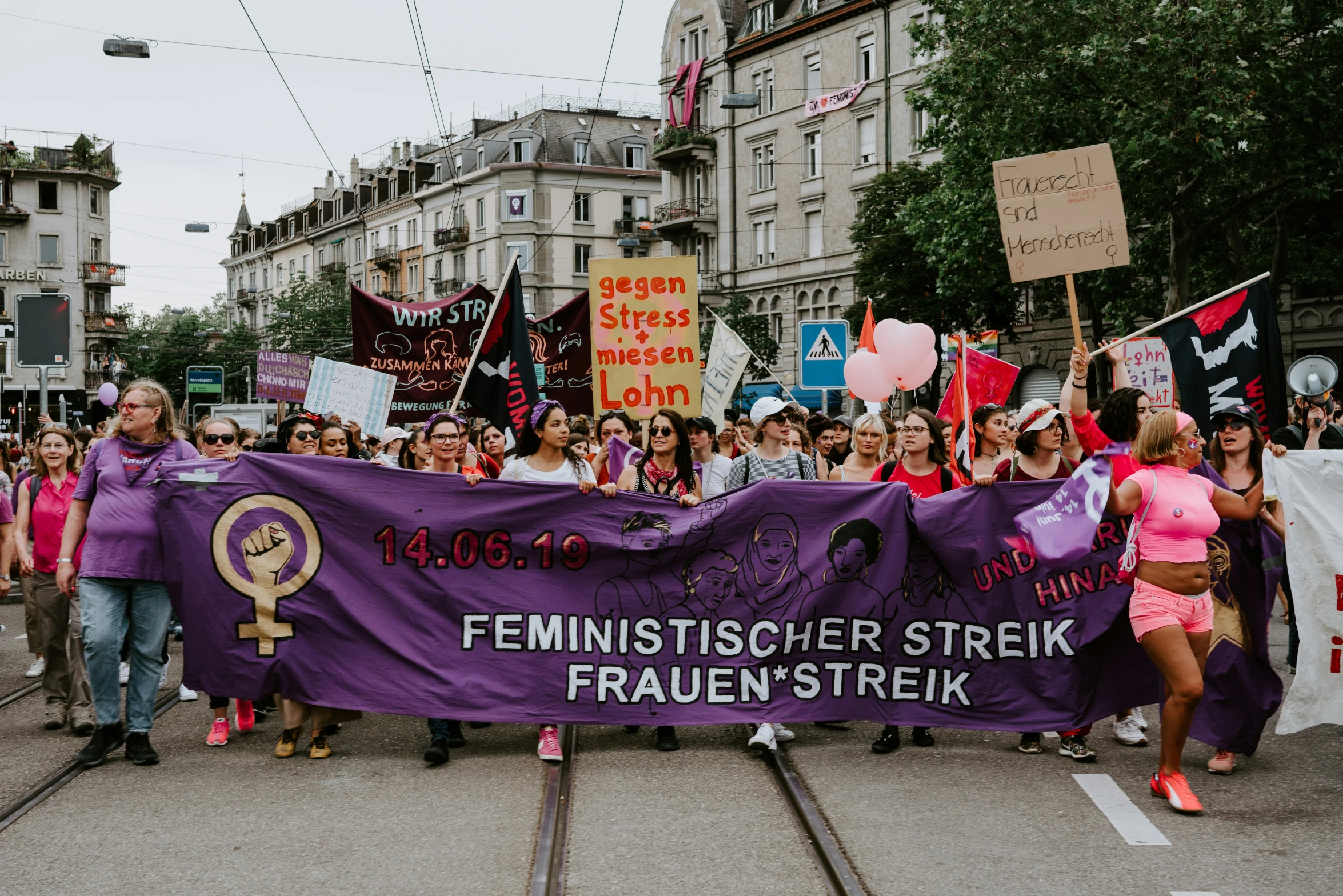 women hold banners and signs while marching down the street