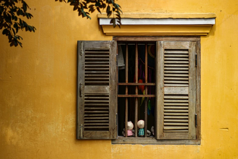 two figurines of people behind bars looking out of an open window