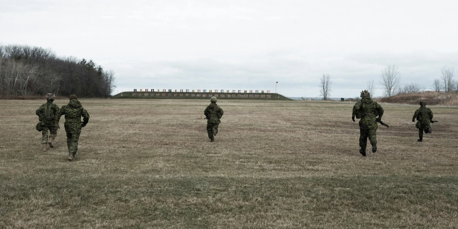 several soldiers in camouflage in a large field