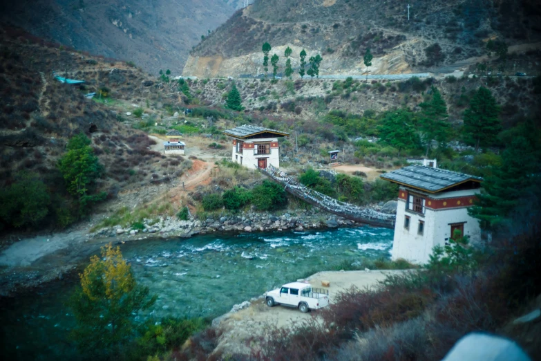 a small house on a river bank surrounded by mountains