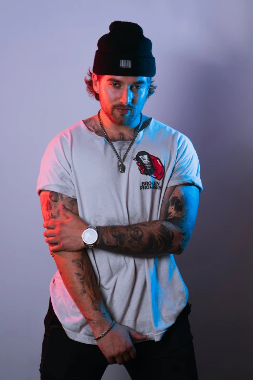 young man with tattoo standing in front of gray wall