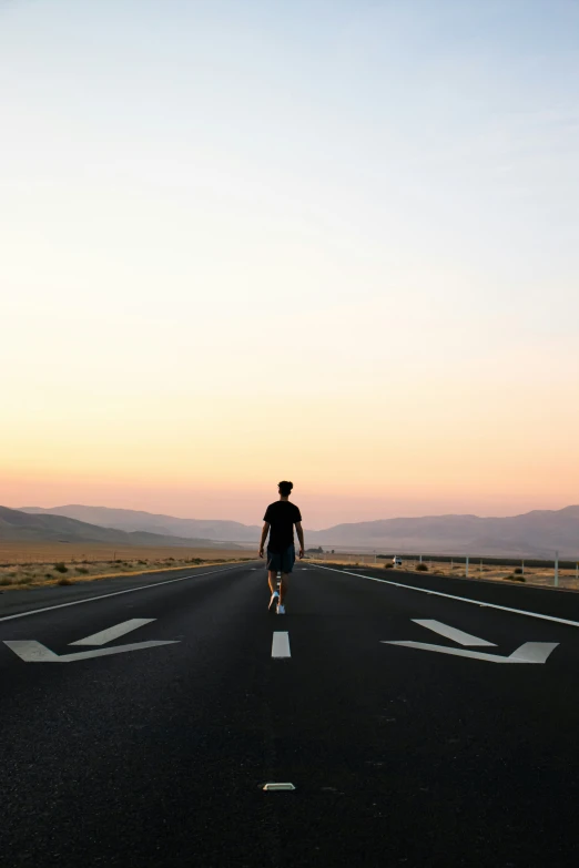 a man walking on an empty road holding an umbrella