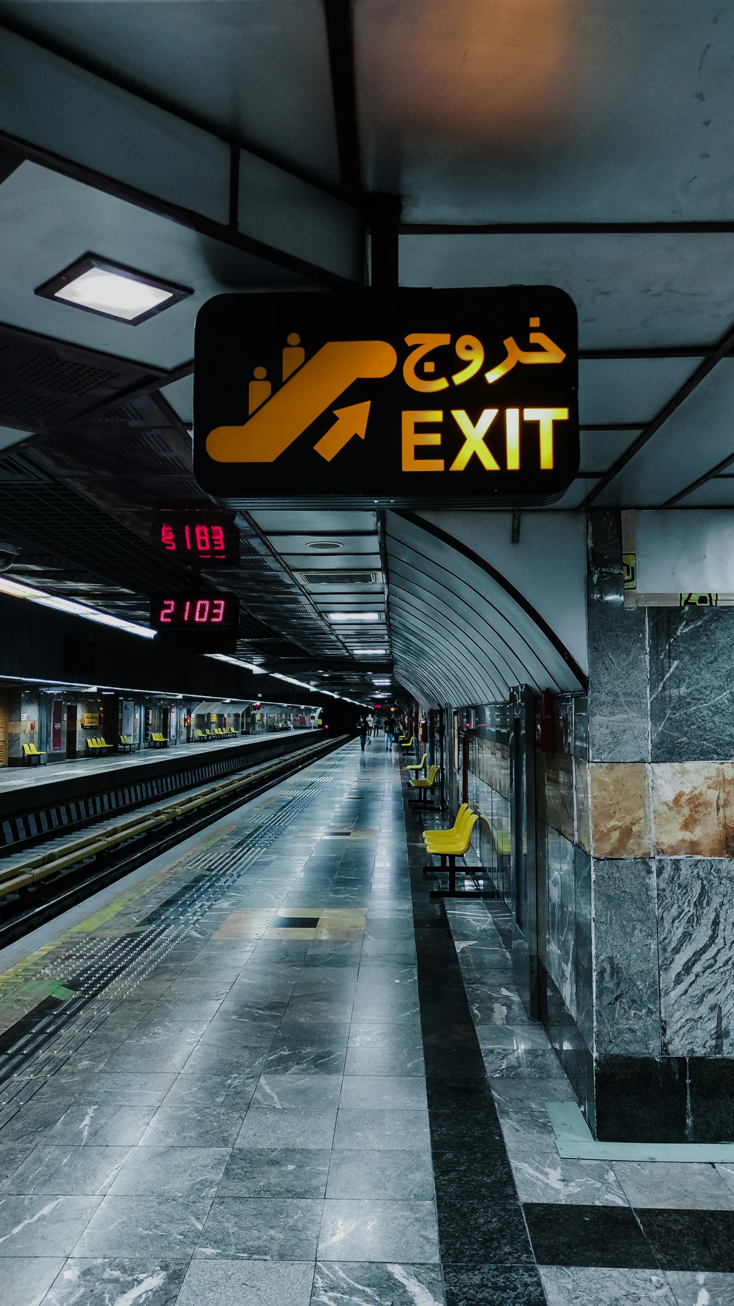 a subway train platform has two large, directional lights above it